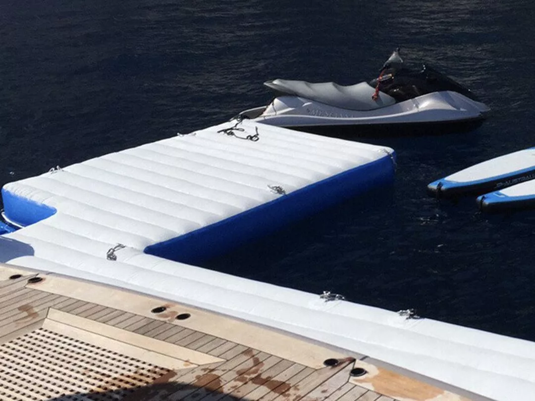 A simple personal watercraft dock attached to a superyacht with a jet ski and stand up paddle boards