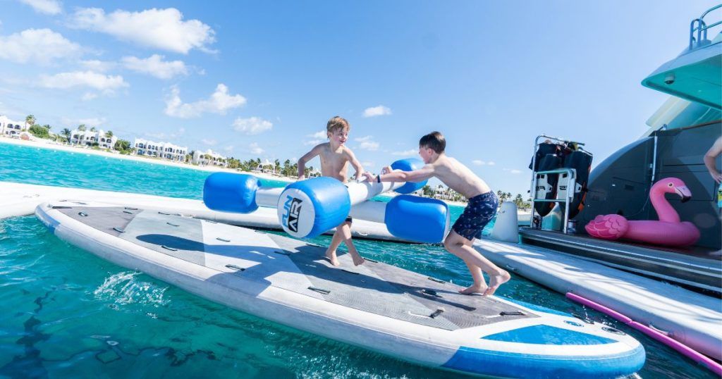 Kids playing with FunAir Water Joust on a standup paddleboard in a superyacht sea pool